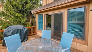 A covered patio with a table and chairs, a barbecue grill, and a sliding glass door. - Your Gateway to Pocono! (Tannersville)