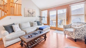 A living room with a sofa, a patterned armchair, a coffee table, and a staircase. - Your Gateway to Pocono! (Tannersville)