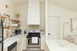 Une cuisine moderne avec des meubles blancs, une cuisinière en acier inoxydable et un plan de travail blanc.