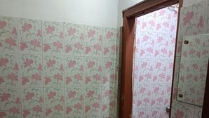 Un baño con baldosas de motivos florales, un lavamanos blanco y una puerta que da a otra habitación.
