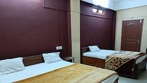 Dos camas individuales con estructura de madera y ropa de cama blanca, una manta marrón sobre una cama y una manta marrón y beige estampada sobre la otra.