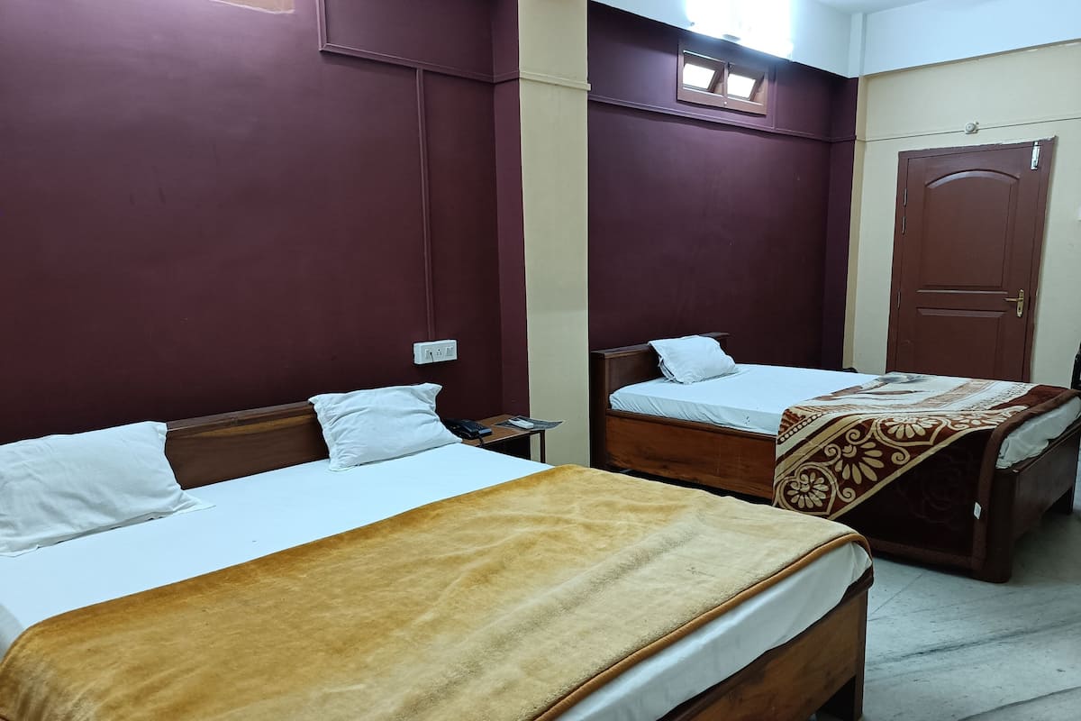 Dos camas individuales con estructura de madera y ropa de cama blanca, una manta marrón sobre una cama y una manta marrón y beige estampada sobre la otra.