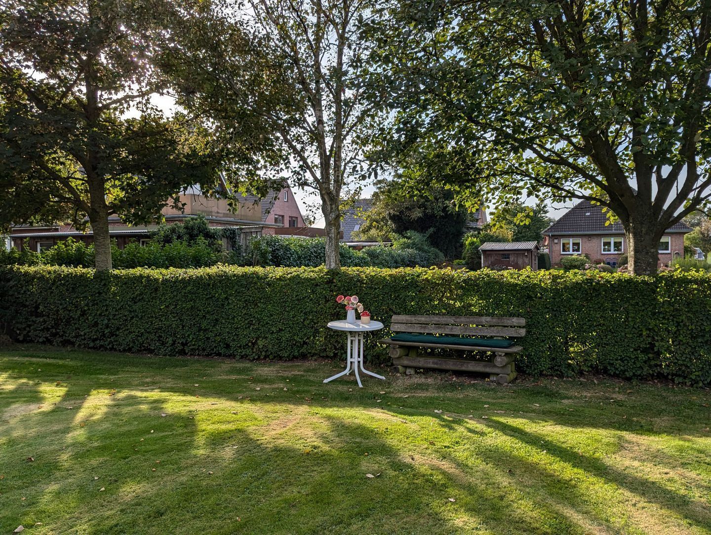 A grassy area with a bench and a small table with flowers.