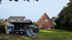 A house with a patio area, a small deck, and a lawn. - Haus Friesenglück, Whg. Leuchtturm - Haus Friesenglück (Alkersum)