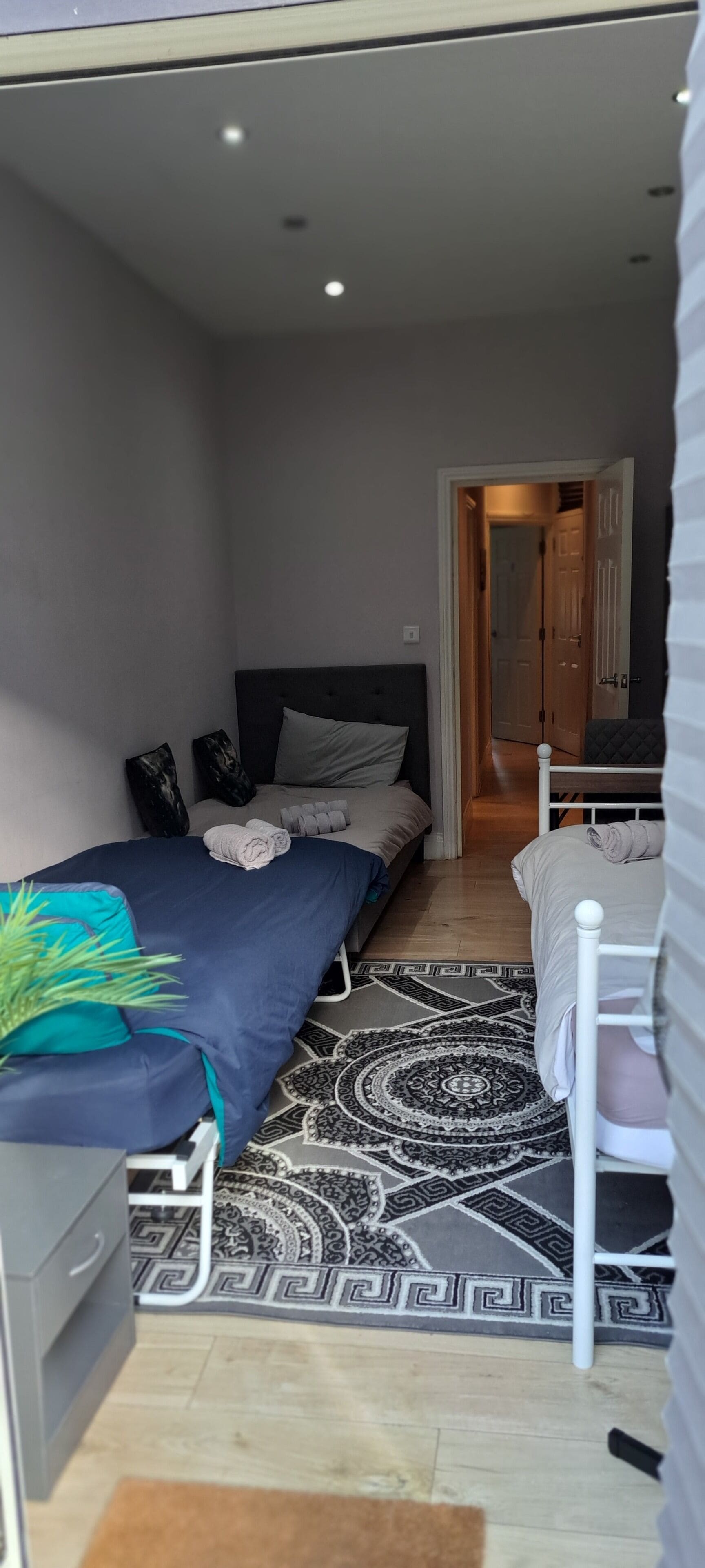 Habitación de hotel pequeña con cama, escritorio, silla y alfombra estampada.