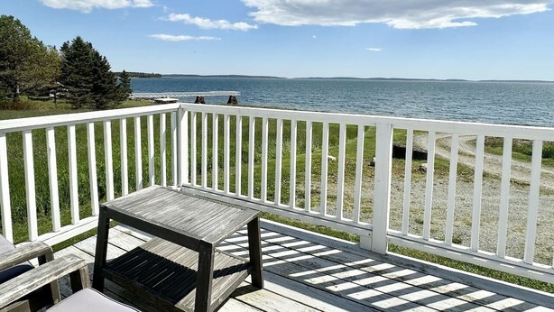A wooden deck with a white railing overlooking a body of water.