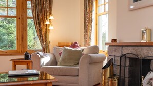 A cozy living room with a fireplace, a sofa, and a coffee table. - Osprey House by Interhome (Nethy Bridge)