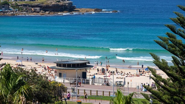 A beach with a lifeguard tower, clear blue water, and a rocky coastline.