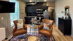 Un salon moderne avec des fauteuils en cuir, une table basse et un tapis à motifs.