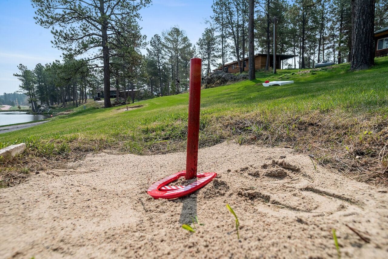 A sandy area with a red post and a red object resembling a flip-flop.