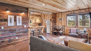 A rustic cabin interior with wooden walls, a dining area, and a cozy seating space.