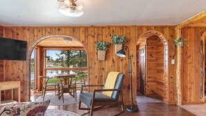 A wooden interior with a dining area, a rocking chair, and a television.