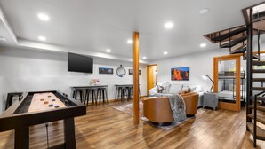 Uma sala de estar acolhedora com mesa de bilhar, assentos confortáveis e uma escada.