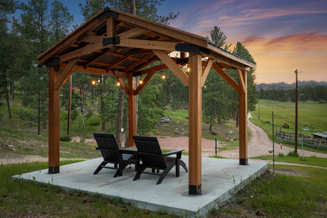 Een houten tuinpaviljoen met twee stoelen en een tafel, omgeven door een natuurlijke omgeving.