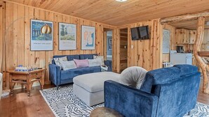 Ein Zimmer mit Holzwänden, einem blauen Sofa, einem kleinen Tisch und Bildern an den Wänden.