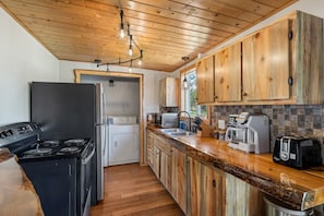 Una cocina con armarios de madera, estufa, refrigerador, lavadora y varios electrodomésticos.