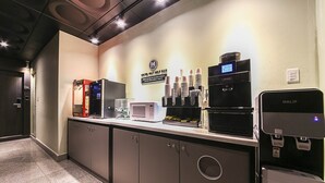 Un'area reception di un hotel con un angolo caffè self-service, un forno a microonde e una macchina da caffè HALIF.