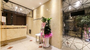 Un'area della reception di un hotel, con scrivania, un piccolo angolo salotto e una pianta decorata con un nastro rosa.