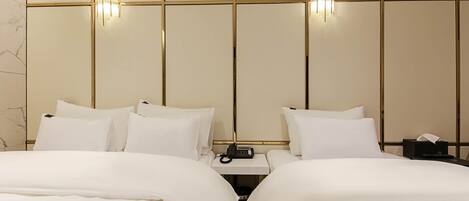 Habitación de hotel con dos camas, una mesita de noche con teléfono e iluminación en la pared.