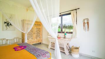 A bedroom with a bed, a nightstand, a window with curtains, a wooden wardrobe, and a wall-mounted decorative item.