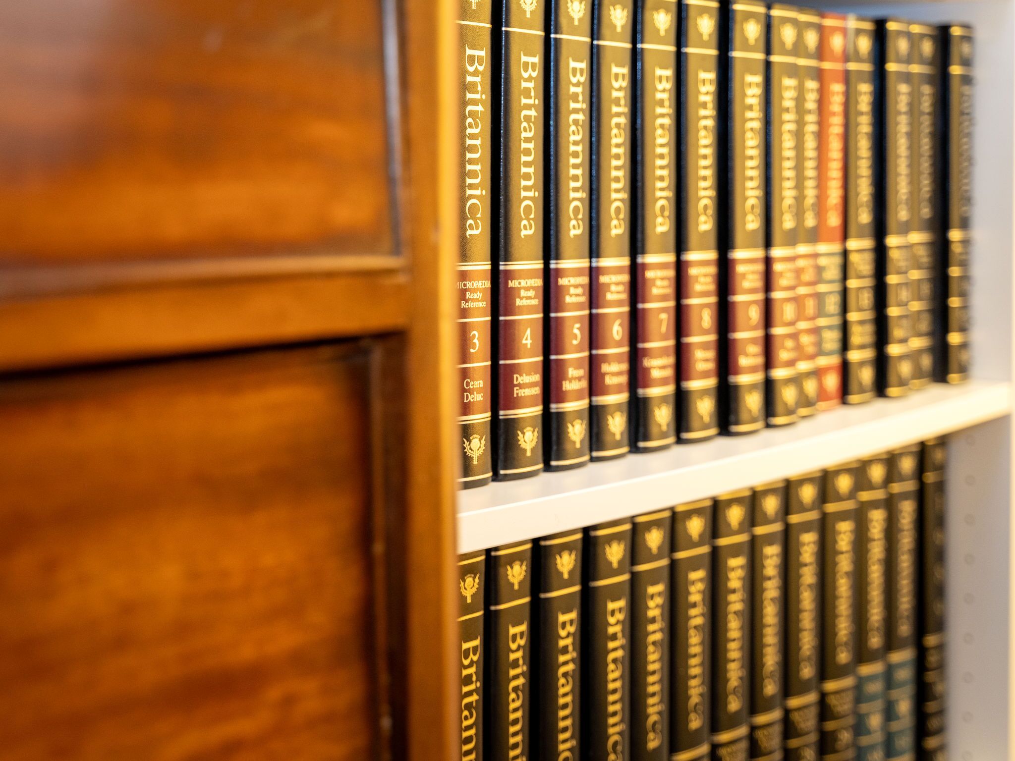 A bookshelf with multiple volumes of 'Britannica' encyclopedias.