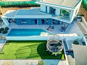 Relax and unwind in a spacious outdoor area with a large pool, trampoline, and lawn.