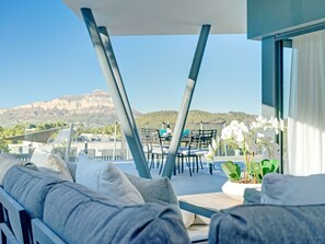 Relax in a serene outdoor space with a sofa and chair, surrounded by a stunning mountain view and lush greenery.