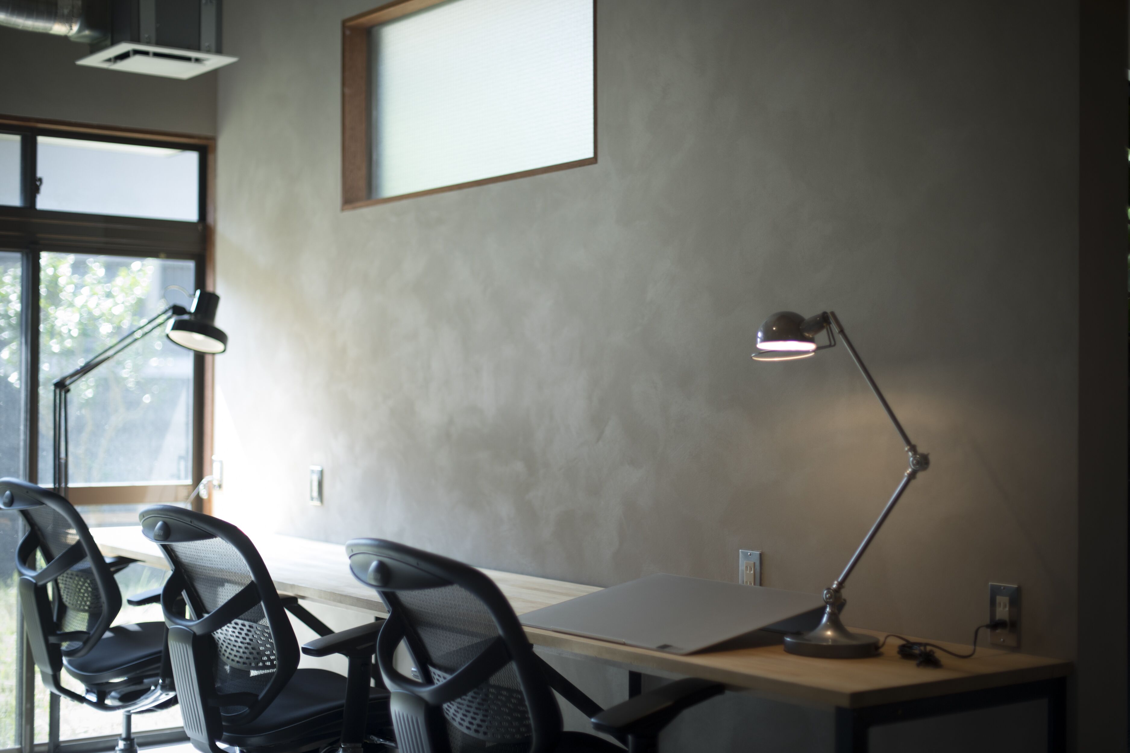 Een werkplek met een bureau, twee stoelen en twee bureaulampen.
