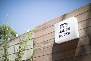 Une enseigne avec l’inscription « AMIGO HOUSE » et une petite illustration représentant un bâtiment.