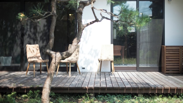 A wooden deck with three wicker chairs and a tree. - AMIGO HOUSE - Hostel (Zushi)