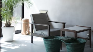 A room with a large window, a potted plant, a chair, a table, and a hanging light fixture. - AMIGO HOUSE - Hostel (Zushi)