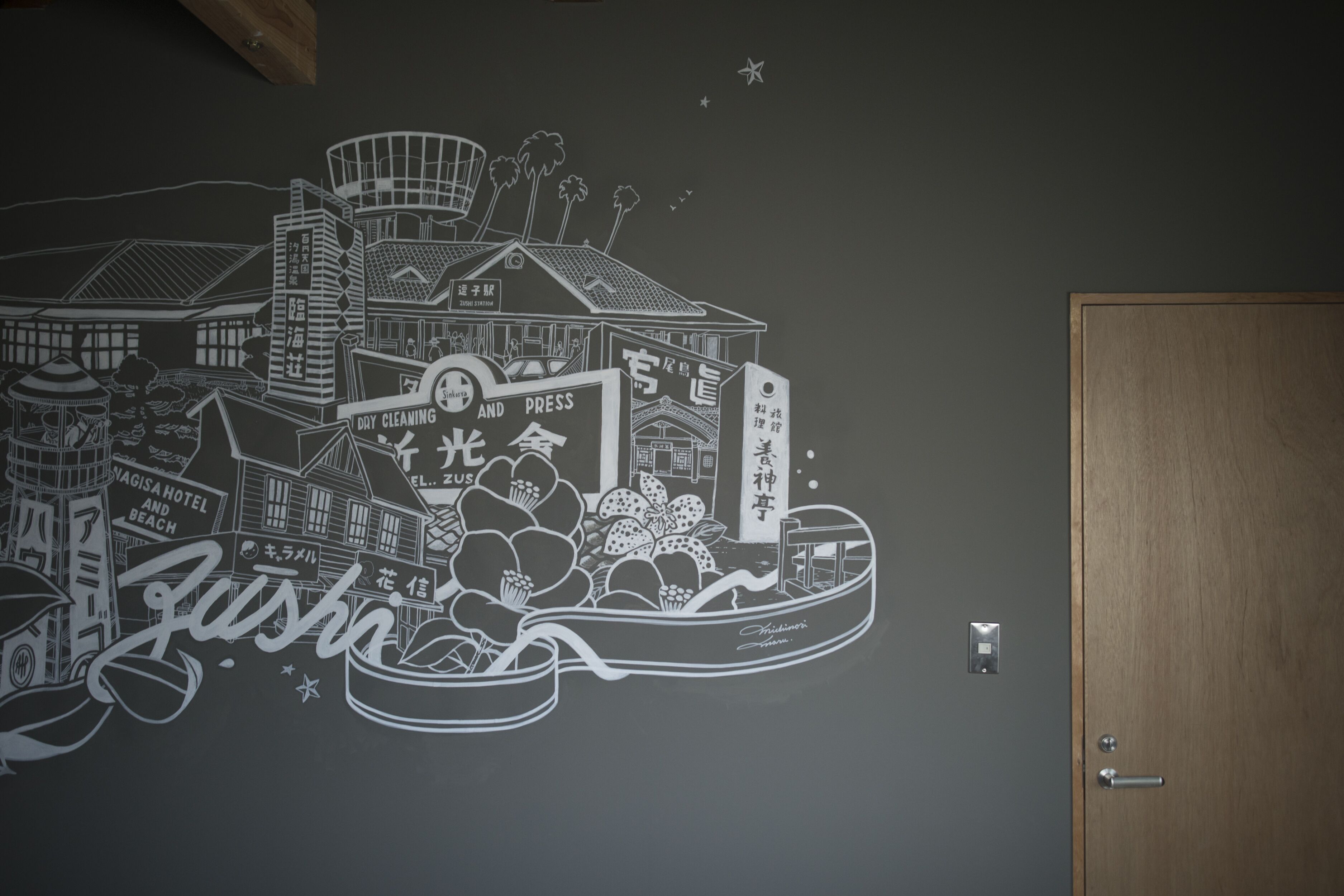 A wall mural depicting a cityscape with buildings, a boat, and various signs in a foreign language.