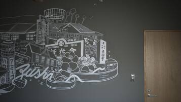 A wall mural depicting a cityscape with buildings, a boat, and various signs in a foreign language.