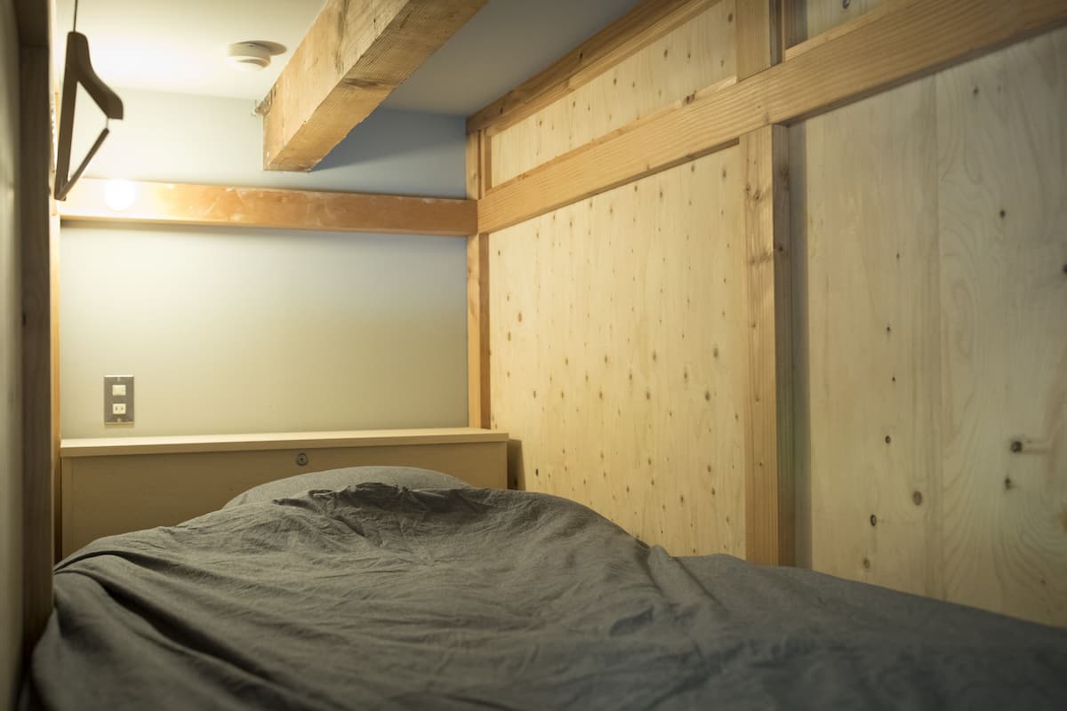 A bedroom with a bed, wooden headboard, and a wardrobe.