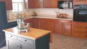 A kitchen with wooden cabinets, a central island, a microwave, and an oven. - Sleeps up to 8 in a safe, quiet area (Kodak)