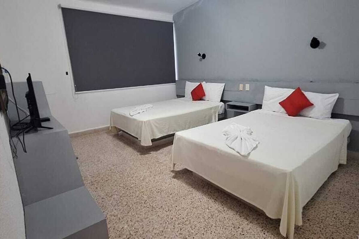 A hotel room with two beds, a TV, and a large window.