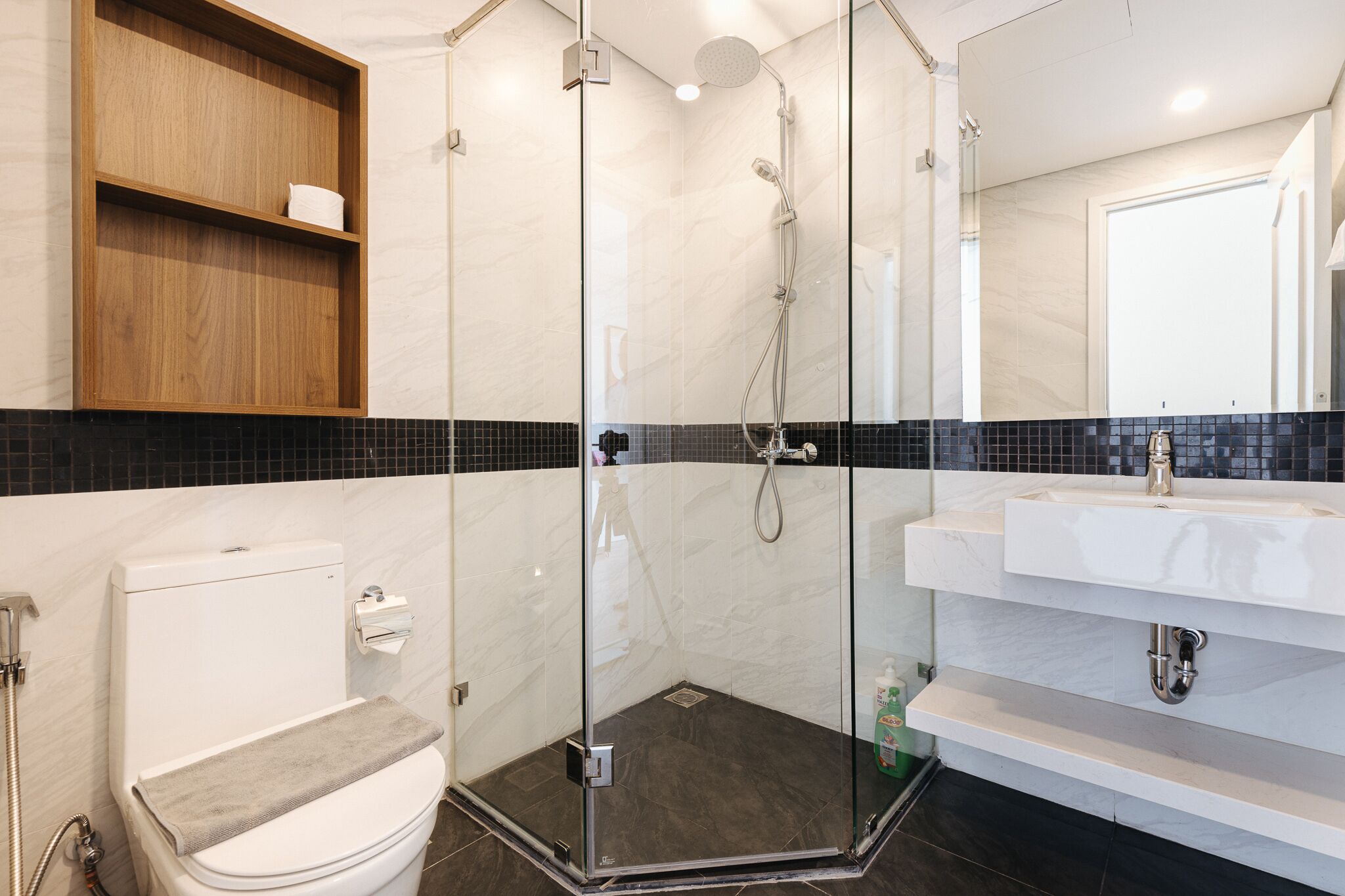 Une salle de bain moderne avec une douche à parois de verre, des toilettes blanches et un meuble-lavabo avec un miroir.