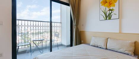 Une chambre d’hôtel avec un grand lit, un balcon avec vue et un tableau encadré au mur.