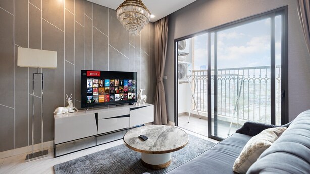 Ein modernes Wohnzimmer mit einem großen Fernseher, einem runden Couchtisch und einem Sofa.