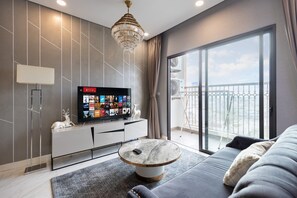 A modern living room with a large TV, a round coffee table, and a sofa. - Muse Hanoi Luxury Apartment - D'Eldorado (Hanoi)