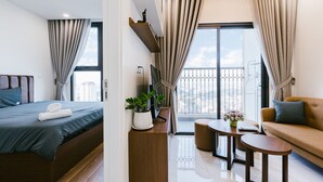 Ein modernes Hotelzimmer mit Bett, einer Couch, einem kleinen Tisch und einem Balkon mit Vorhängen.