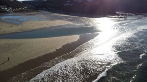 Una playa con agua cristalina, una orilla de arena y una persona caminando.