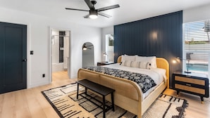Una camera da letto con un letto, un comodino, una ventola a soffitto e vista sull'esterno.
