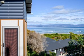 A coastal property with a view of the ocean, a wooden door, and a metal roof.