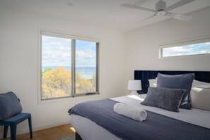 Une chambre à coucher avec un lit, une chaise, une table de chevet, une lampe et un ventilateur de plafond.