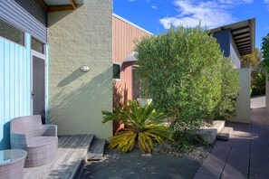 Un espace patio aménagé avec du mobilier d’extérieur, un petit palmier et une plante en pot.