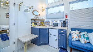 Een kleine keuken met een magnetron, koffiezetapparaat en een koelkastje.