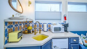 Een kleine keuken met een magnetron, broodrooster en spoelbak.