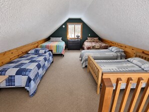 A dormitory room with two single beds, a dresser, and a window.