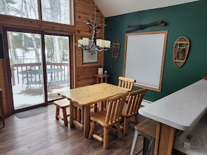 A wooden interior with a dining table and chairs, a chandelier, and a view of the outdoors through large windows. - Bayview  1 (Mercer)